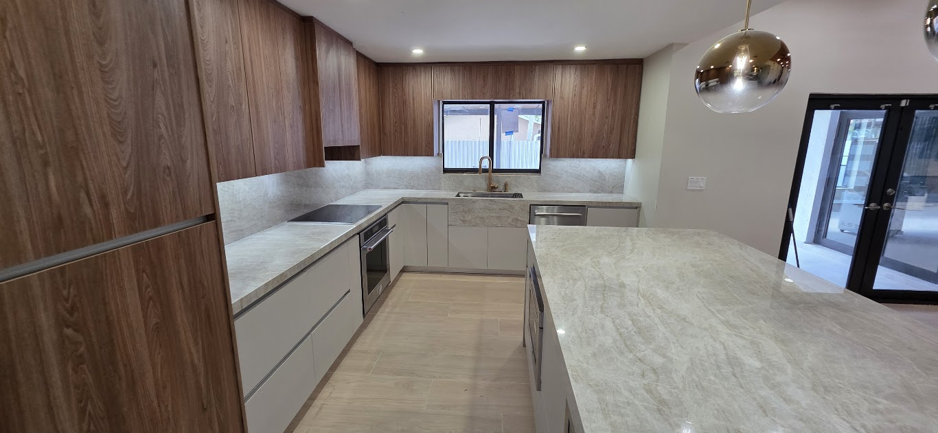 European-style kitchen with wood-grain upper cabinets, light lower cabinets and a large stone island