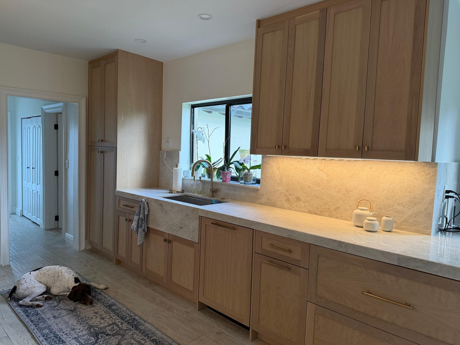 Natural wood cabinetry with stone backsplash and brass faucet